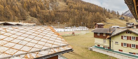 Un pueblo de montaña con edificios tradicionales, una instalación deportiva y vistas del bosque circundante.