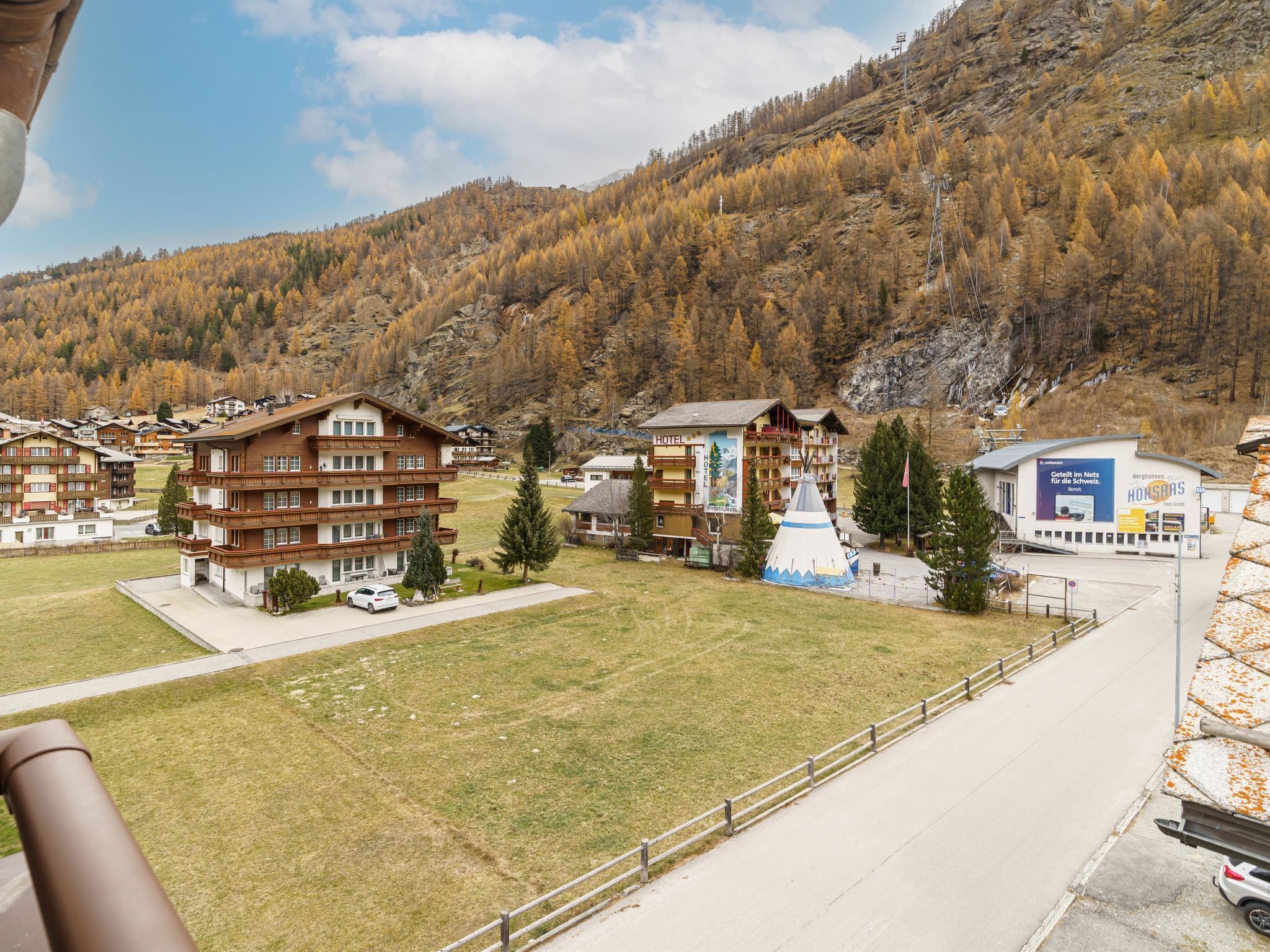 A hotel with multiple floors, a ski lift, and a mountainous backdrop.