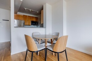 Eine moderne Küche mit Holzausstattung, Edelstahlgeräten und einem runden Esstisch mit zwei Stühlen.