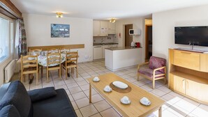 Un espace de vie compact comprenant un coin repas, une kitchenette et un téléviseur.