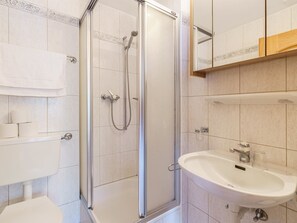 Ein Badezimmer mit einer Duschkabine, einem weißen Waschbecken und einer Toilette.