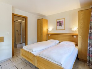 Ein Hotelzimmer mit einem hölzernen Bett, einer Dusche und einem gerahmten Bild an der Wand.