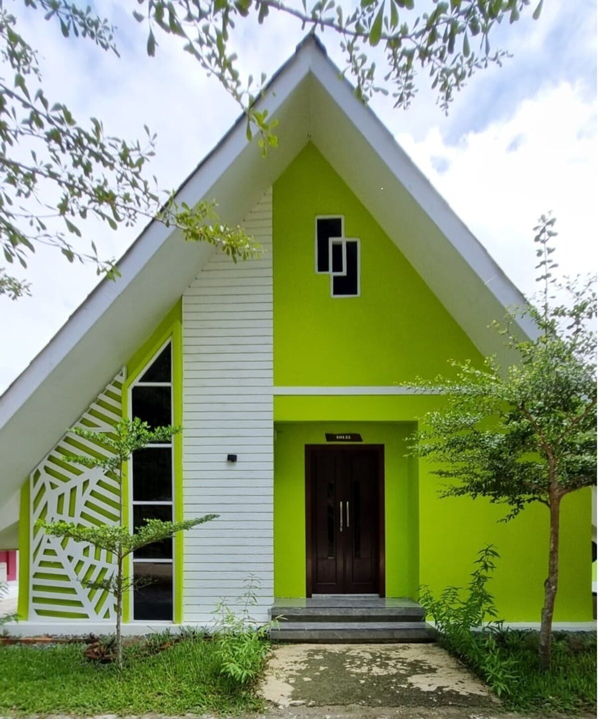 A building with a green facade, a white trim, and a dark brown door.