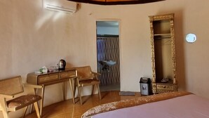 Una habitación con cama, escritorio, silla, espejo y ventana.