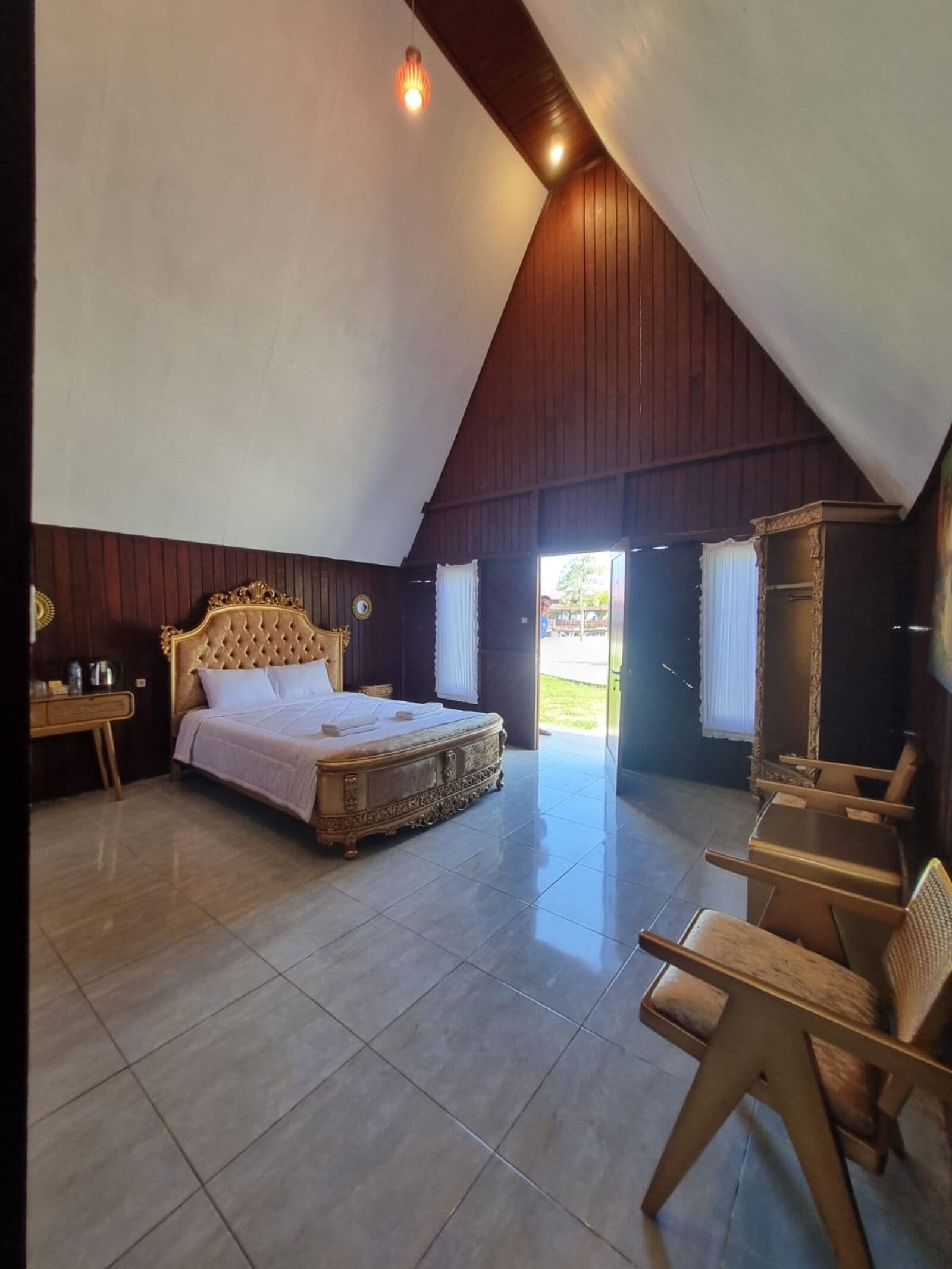 Ein Schlafzimmer mit einem großen Bett, Holzwänden und einer schrägen Decke.