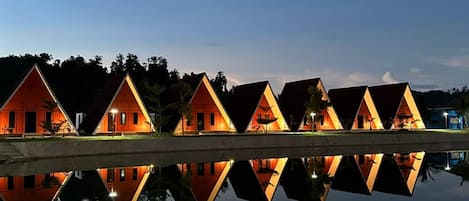 Un hilera de edificios de forma triangular con una superficie acuática reflectante al frente.