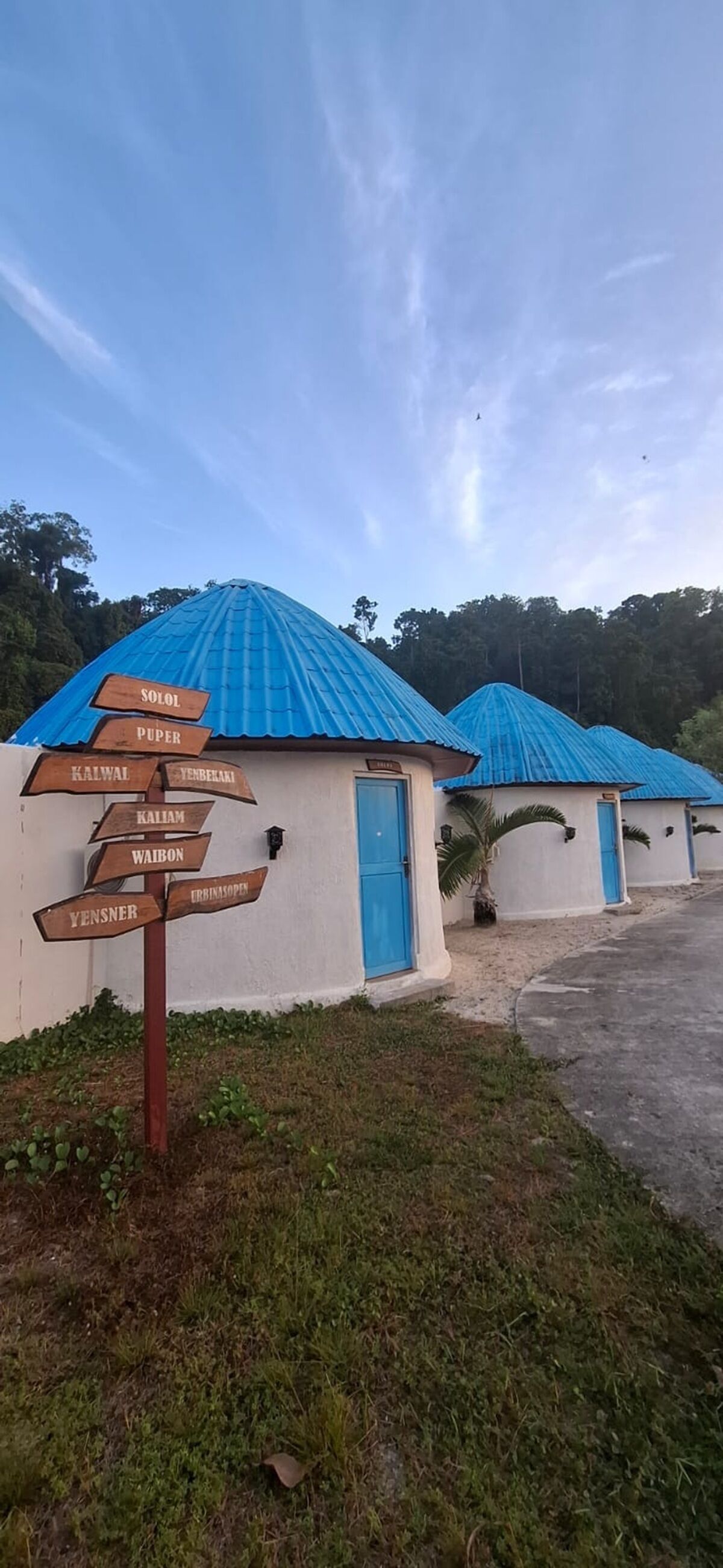 A row of buildings with blue roofs and a directional signpost with multiple destinations.