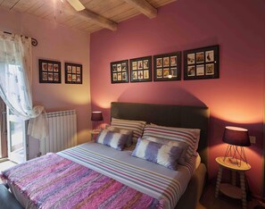 A bedroom with a bed, a bedside table, a lamp, a window with curtains, and a wall with framed pictures. - Beautiful 3-bedroom house with AC in charming Silvignano (Silvignano)