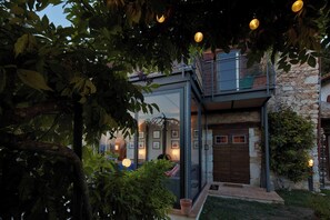 A modern house with a glass entrance, a stone wall, and a wooden door. - Beautiful 3-bedroom house with AC in charming Silvignano (Silvignano)