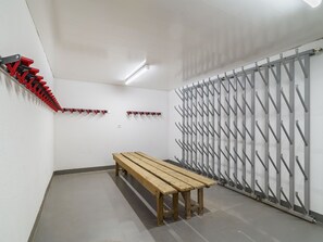 A room with a wooden bench, a red and black coat rack, and a grey metal rack with hooks. - Haus Astoria by Interhome (Saas-Grund)