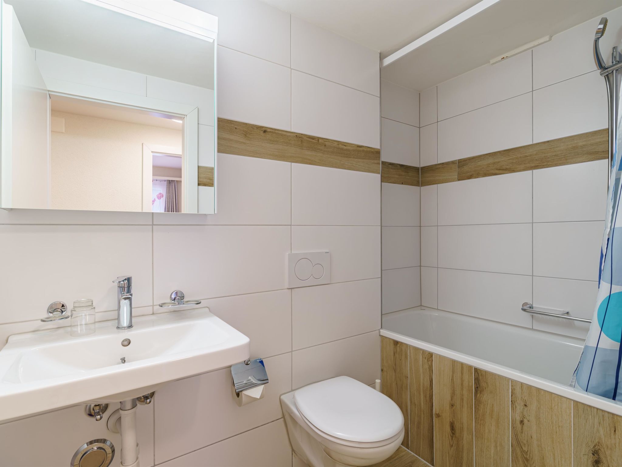 Un baño con lavamanos blanco, inodoro y zona de ducha.