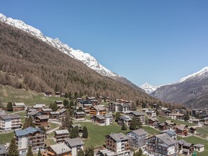 Un village de montagne aux bâtiments de style chalet, une station de ski et, en arrière-plan, des montagnes enneigées.
