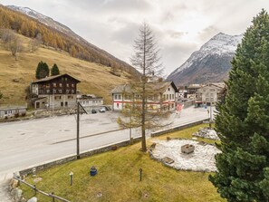 A mountain village with traditional buildings, a parking lot, and a view of snow-capped mountains. - Haus City by Interhome (Saas-Grund)