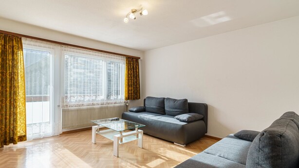 A modern living room with a sofa, a glass coffee table, and a radiator. - Haus City by Interhome (Saas-Grund)
