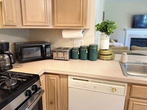 A kitchen with a stove, microwave, toaster, and a dishwasher.