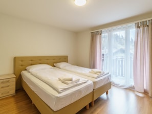 A hotel room with two beds, a wooden dresser, and a large window with curtains. - Haus Astoria by Interhome (Saas-Grund)