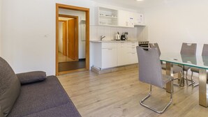 A modern kitchen with white cabinets, a dining table with chairs, and a wooden door leading to another room. - Haus Slalom by Interhome (Saas-Fee)
