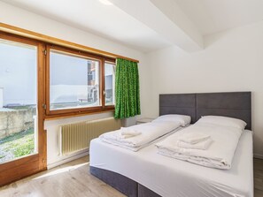 A bedroom with a large window, a radiator, and a bed with neatly folded towels. - Haus Slalom by Interhome (Saas-Fee)