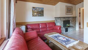 Ein Wohnzimmer mit einem roten Ledersofa, einem Holztisch, einem Kamin und einem Gemälde an der Wand.