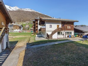 A chalet-style building with a wooden facade, a staircase, and a view of snow-capped mountains in the background. - Haus Alfa by Interhome (Saas-Fee)