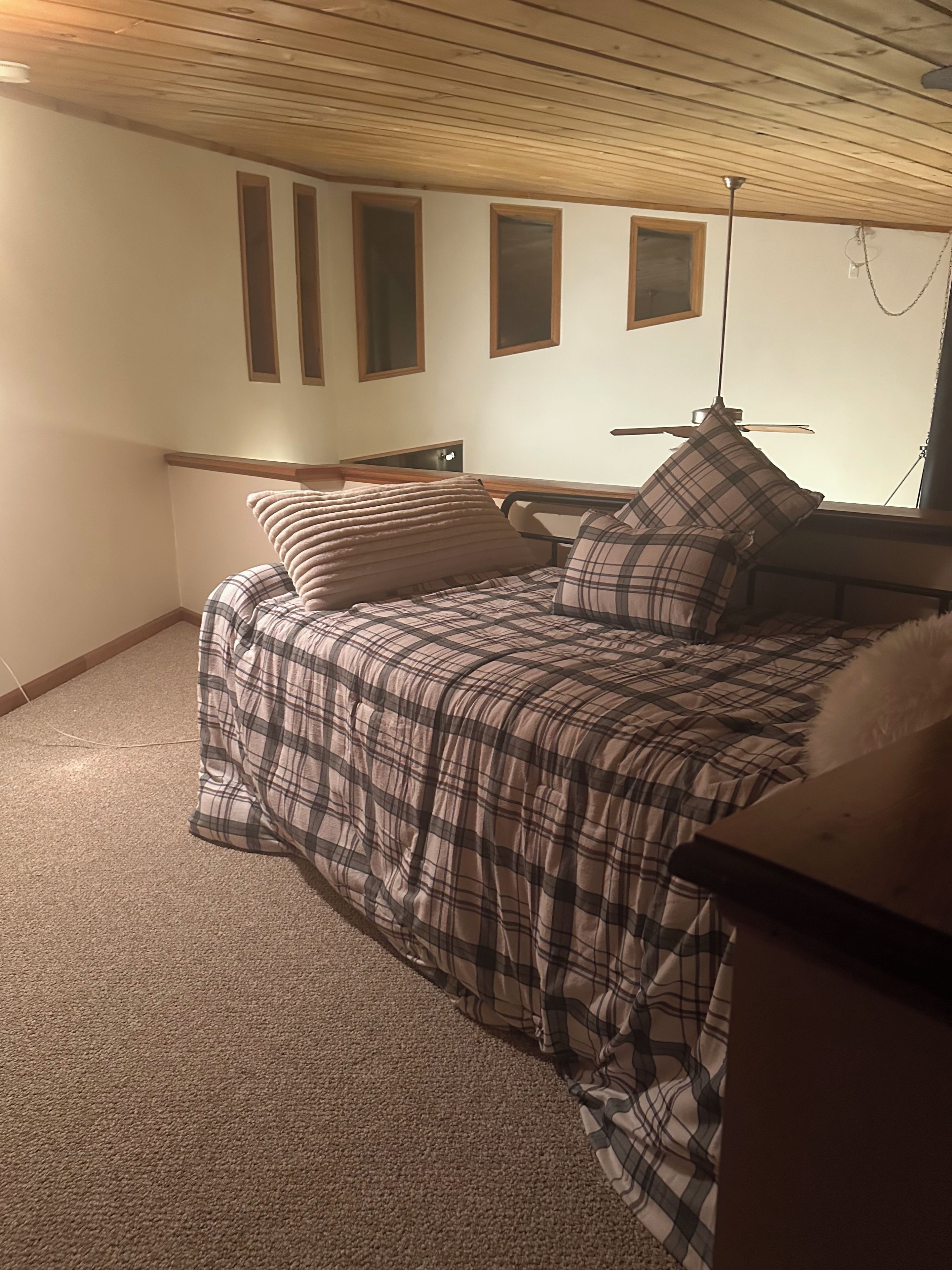 A bedroom with a bed, a ceiling fan, and a window.
