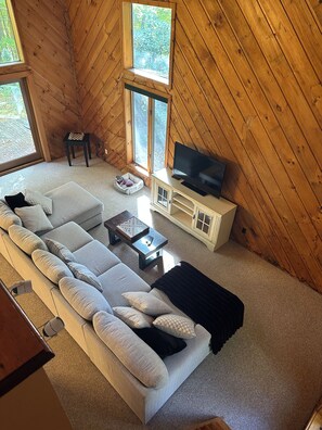 A cozy, wooden-paneled room with a large sofa, a television, and a small table. - Lovely 4-bedroom house in Mendon perfect for your getaway (Mendon)