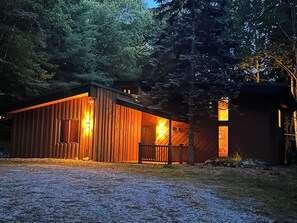 A wooden cabin with a porch and a small adjacent structure, surrounded by trees. - Lovely 4-bedroom house in Mendon perfect for your getaway (Mendon)