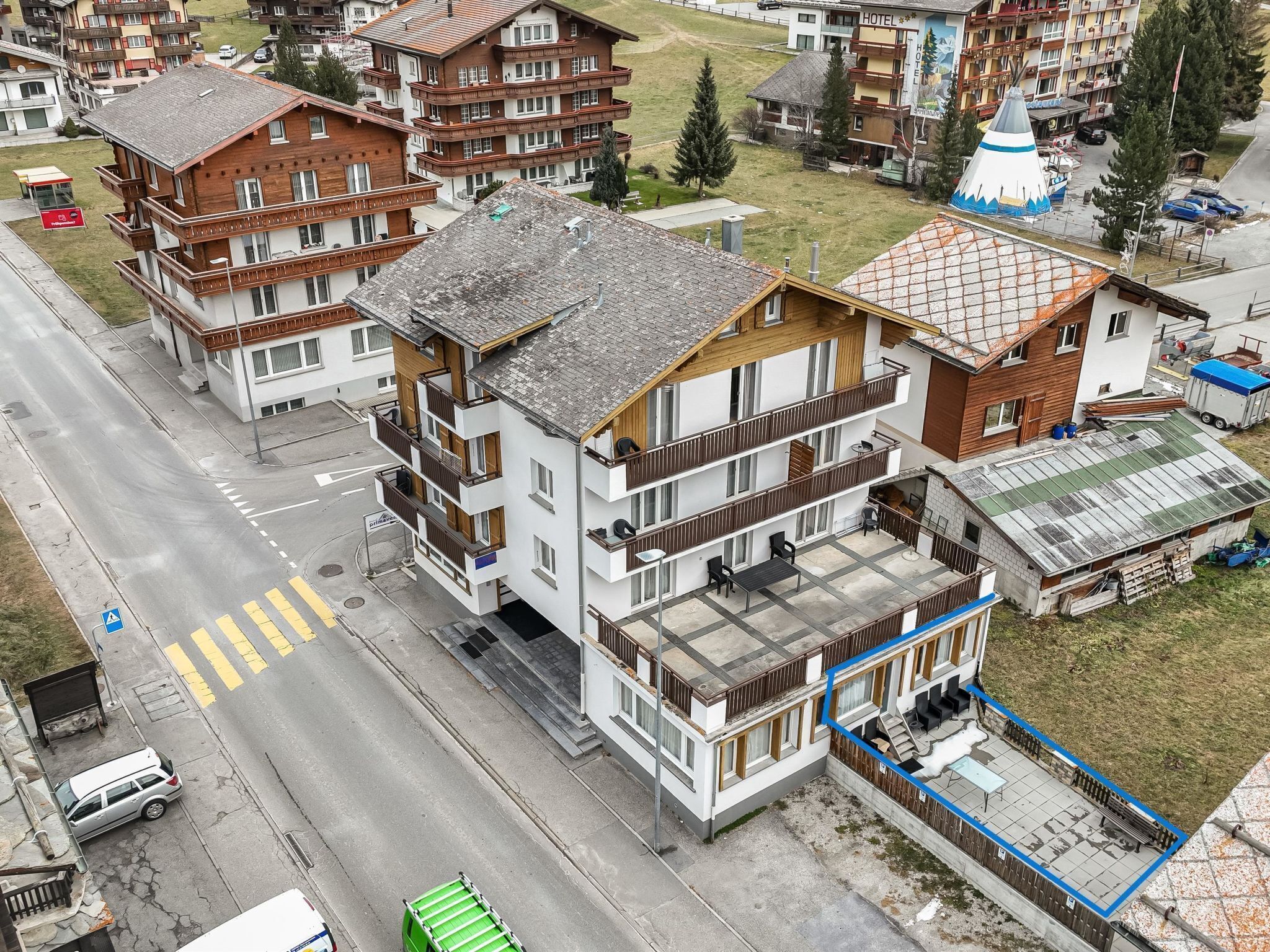 Ein mehrstöckiges Hotel mit Balkonen, einem Parkplatz und einer Straße mit Zebrastreifen.
