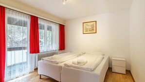 Een slaapkamer met een bed, nachtkastje, radiator en een raam met gordijnen.