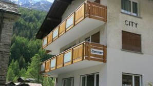 Een gebouw met twee verdiepingen en een balkon, waarop 'CITY' en 'Zimmer' staan.