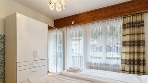 Ein Schlafzimmer mit Bett, Kleiderschrank und einem fenster mit Vorhängen.