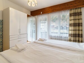 Ein Schlafzimmer mit Bett, Kleiderschrank und einem fenster mit Vorhängen.