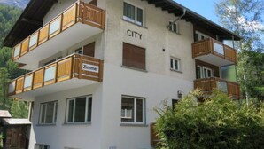 Ein mehrstöckiges Gebäude mit Balkonen und einem Schild, auf dem 'CITY' und 'Zimmer' steht.