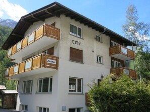 Ein mehrstöckiges Gebäude mit Balkonen und einem Schild, auf dem 'CITY' und 'Zimmer' steht.