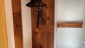 Een houten kast met een kledingroede en een witte deur met houten frame.