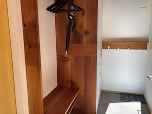 Ein Holzschrank mit Kleiderstange und einer weißen Tür mit Holzrahmen.