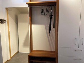 A walk-in closet with a wooden shelf, a hanging rack, and a wardrobe with drawers. - Ferienwohnung Dorfbrunnu Appartement/Fewo, Dusche, WC 4-Bettwohnung, Dusche, WC by Interhome (Ried-Brig)