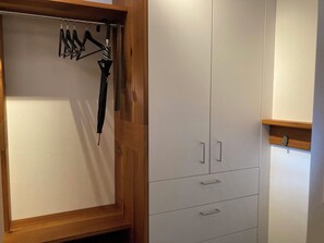 Ein Schrank mit Holzrahmen, Kleiderstange und einer weißen Tür.