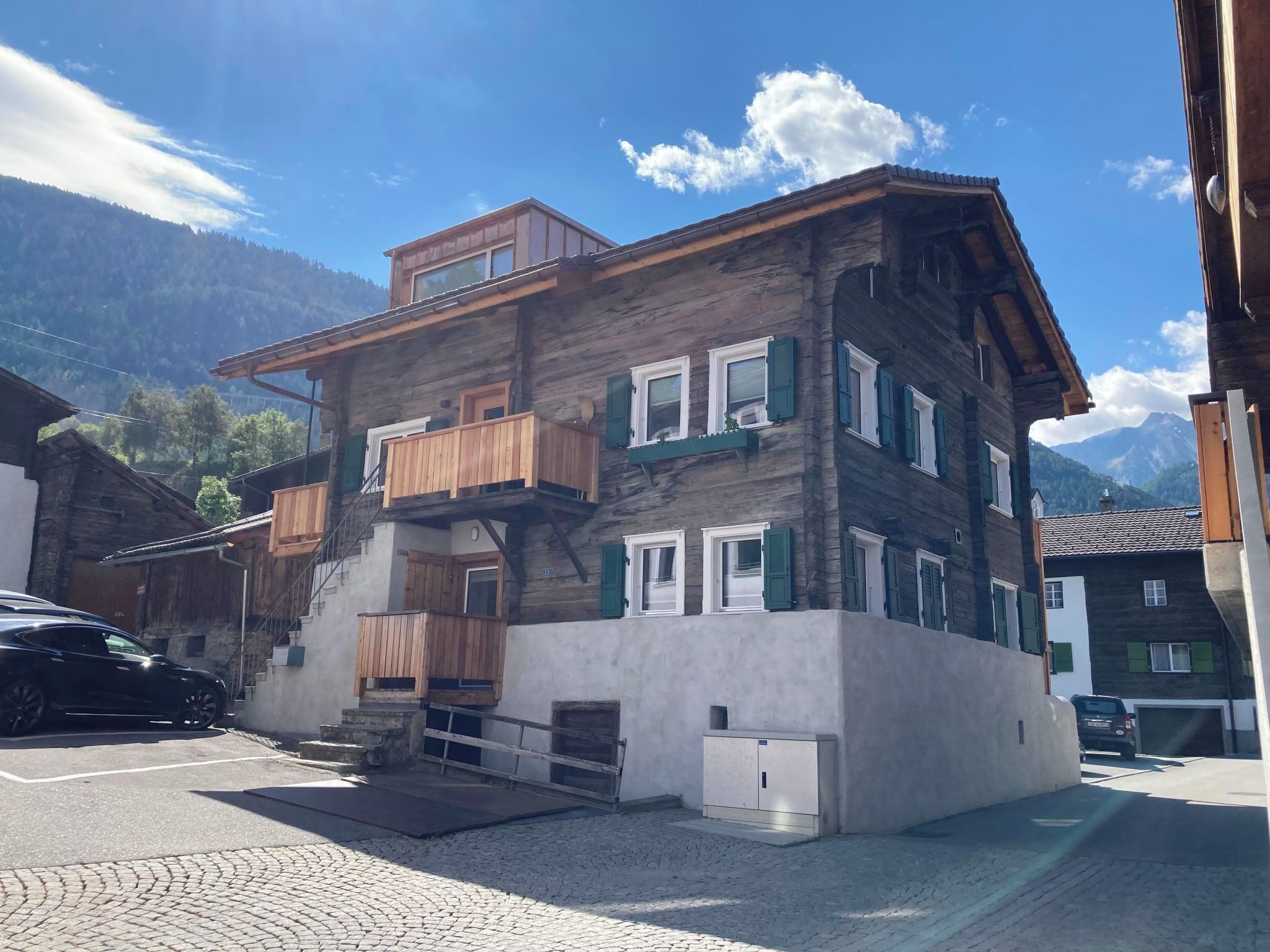 Un edificio a più piani con un balcone, una scala e un garage.