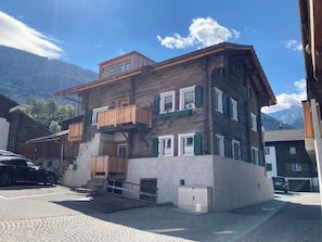 Ein mehrstöckiges Gebäude mit Balkon, Treppe und Garage.