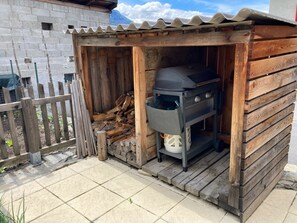 Ein hölzerner Kochbereich im Freien mit Grill und Holzstoß.