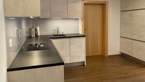 Een moderne keuken met een zwart aanrecht, roestvrijstalen apparatuur en licht houten keukenkastjes.