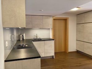 Eine moderne Küche mit schwarzer Arbeitsplatte, Edelstahlgeräten und hellen Holzschränken.
