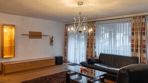 Uma sala de estar moderna com uma mesa de centro de vidro, sofá de couro e um lustre.