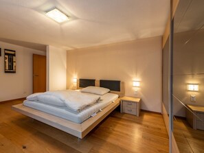 A modern bedroom with a bed, bedside tables, and a nightstand. - Villa Alpenhof by Interhome (Saas-Almagell)