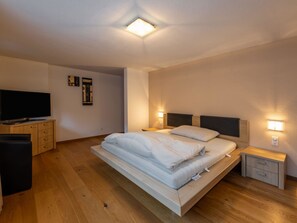 Une chambre à coucher moderne avec un lit, des tables de chevet, un téléviseur et des œuvres d’art accrochées au mur.
