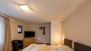 Quarto de hotel com cama, televisão, escrivaninha e cadeira.
