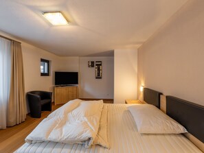 A hotel room with a bed, a TV, a desk, and a chair. - Villa Alpenhof by Interhome (Saas-Almagell)