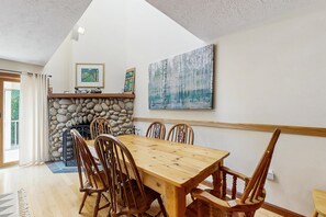 Ein Essbereich mit Holztisch und -stühlen, einem Steinofen und Kunstwerken an den Wänden.