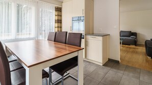 A modern kitchen with a dining area, a sofa, and a view of the outside. - Haus City by Interhome (Saas-Grund)